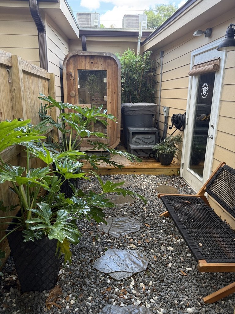 The planted outdoor recovery courtyard with cedar sauna and cold plunge at Fitz Fitness